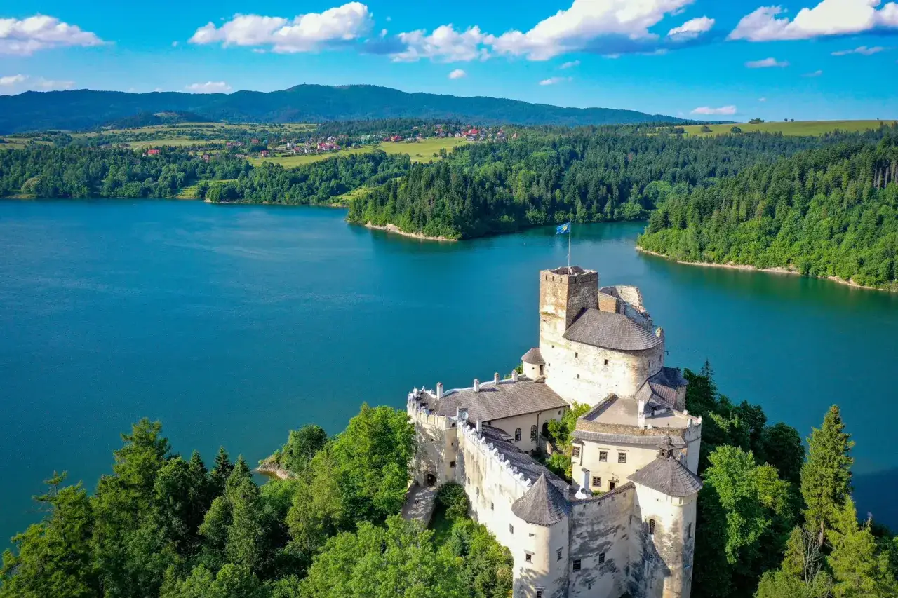 Zamek w Niedzicy g&oacute;ruje nad turkusowym jeziorem czorsztyńskim, otoczony zielonymi lasami i pag&oacute;rkami.