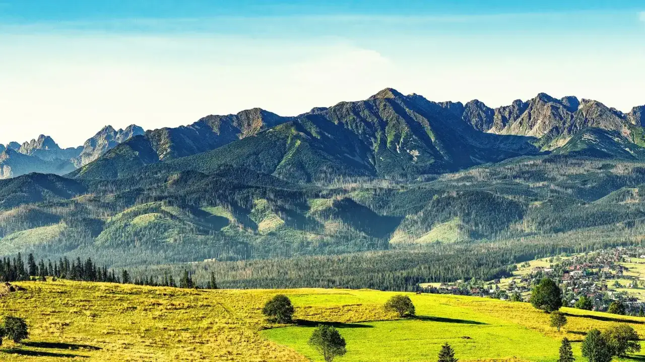 Idealny widok na długi weekend: zielone łąki, lasy i majestatyczne Tatry.