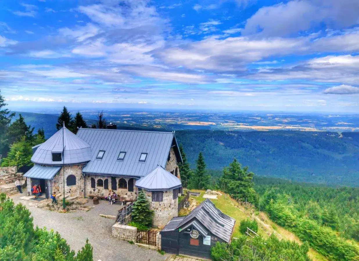Kamienny schron turystyczny na szlaku na Wysoki Kamień, z widokiem na rozległą panoramę Gór Izerskich.
