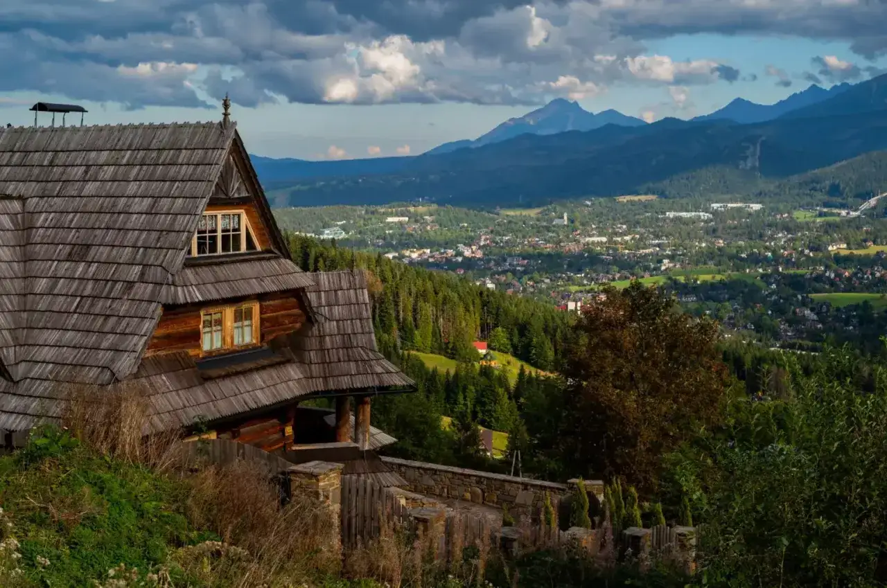 Drewniany hotel ze spa w górach, z widokiem na miasteczko i Tatry.