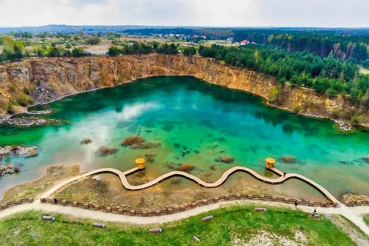 Malowniczy park Gródek Jaworzno z turkusową wodą i drewnianą kładką.