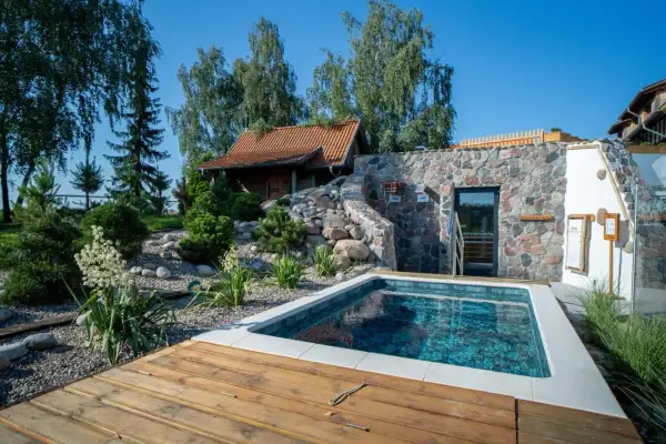 Relaks w klimatycznym spa w Polsce: basen, kamienna ściana z sauną i drewniany taras.