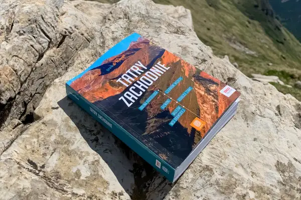 Przewodnik "Tatry Zachodnie" leży na kamieniach, gotowy do odkrywania górskich szlaków.