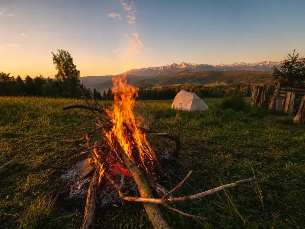 Ognisko i namiot na punkcie widokowym Łapszanka. W tle majestatyczne Tatry o zachodzie słońca.