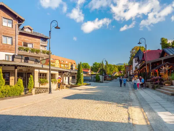 Urokliwe miasta w górach, z brukowaną uliczką, drewnianymi domami i zielenią.