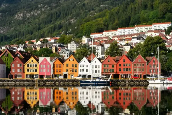 Kolorowe kamienice Bryggen w Bergen, wpisane na listę UNESCO, odbijają się w wodzie. Idealne miejsce, by zobaczyć, co oferuje to norweskie miasto.