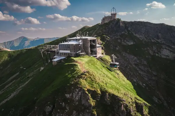 Kasprowy Wierch widok ze szczytu. Kolejka linowa wjeżdża na szczyt, gdzie znajdują się budynki obserwatorium i stacji meteorologicznej.